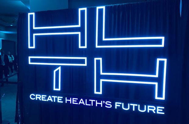 AHA Market Scan More Big Market Transformation Moves in Store Next Year. HLTH Create Health's Future neon sign.