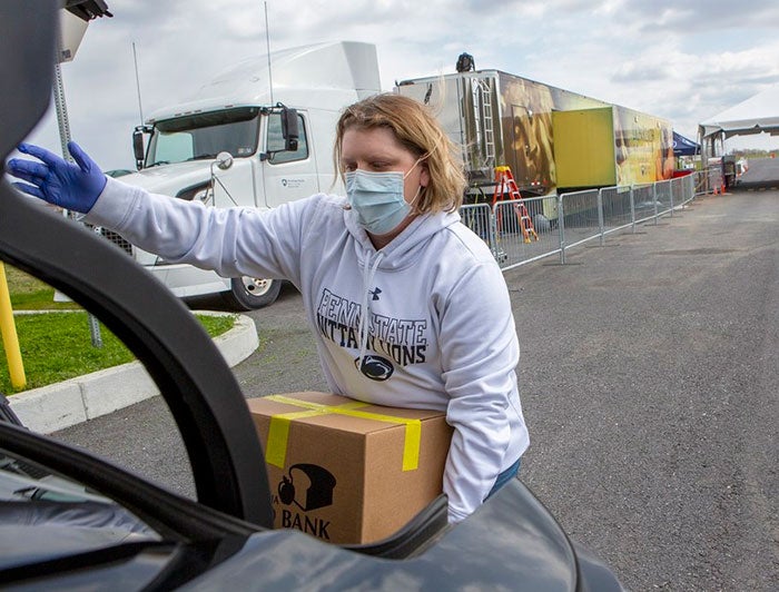 Person packing a box into a cars trunk during COVID-19