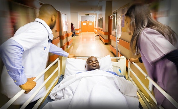 Stakeholders Target Health Disparities During Pandemic. Emergency room clinicians transfer an African-American patient down a hospital corridor.