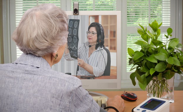 Is Your Telehealth Program Built for the New Health Care World? An elderly woman uses her computer for a telehealth appointment with her doctor, who is review the patient's X-Rays.